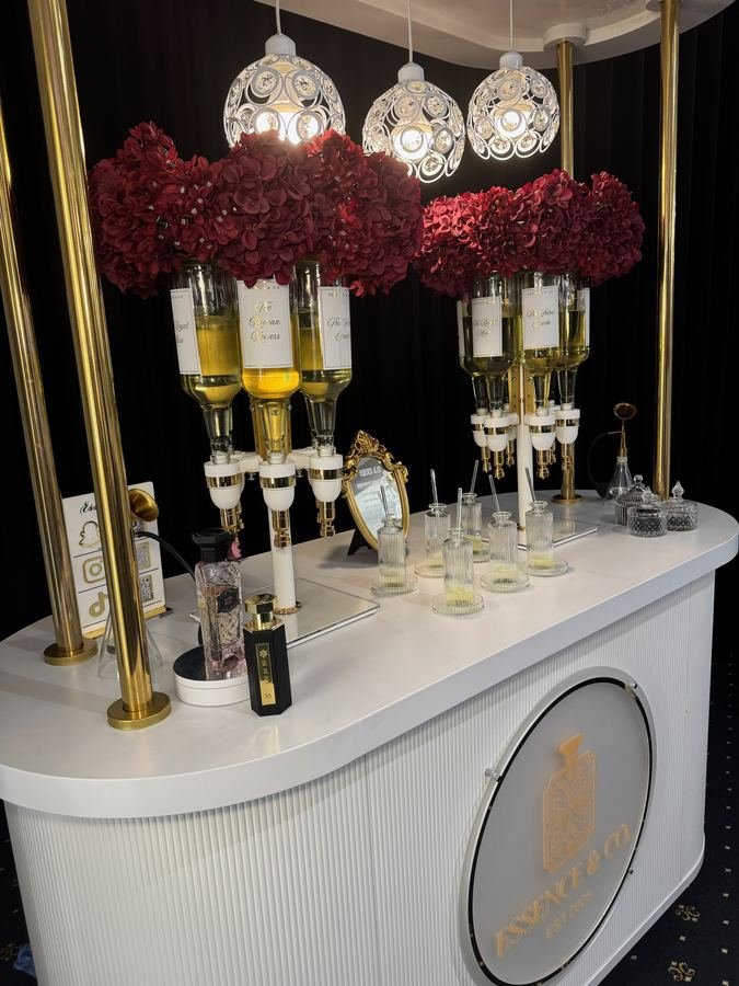 Essence & Co. perfume bar with gold dispensers, deep red hydrangeas and illuminated pendant lighting